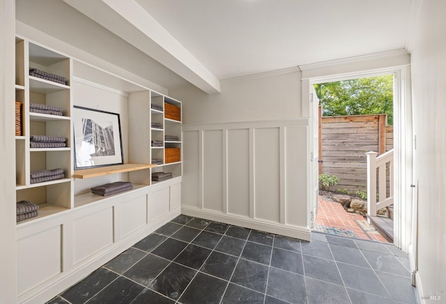 mudroom with dark tile patterned floors, a decorative wall, and a wainscoted wall