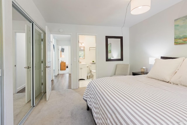 bedroom featuring a closet, ensuite bath, and light colored carpet