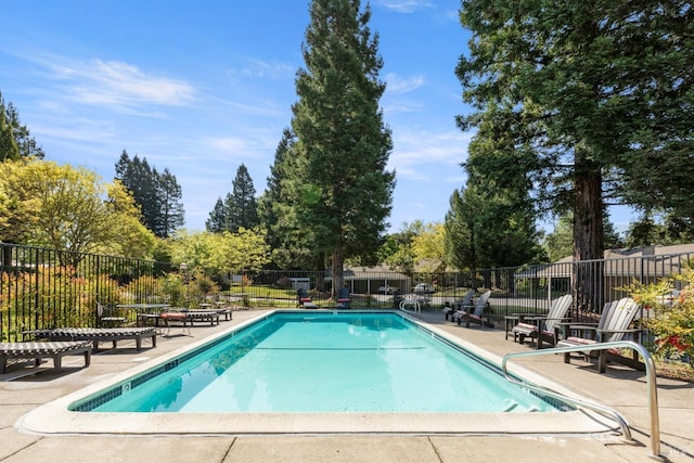 community pool with a patio area and fence