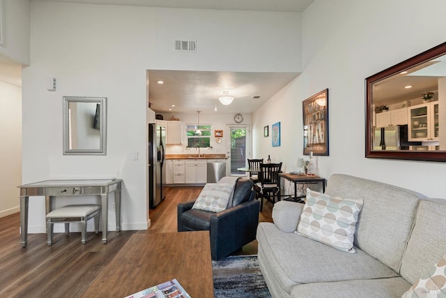 living area with recessed lighting, a high ceiling, dark wood finished floors, and visible vents