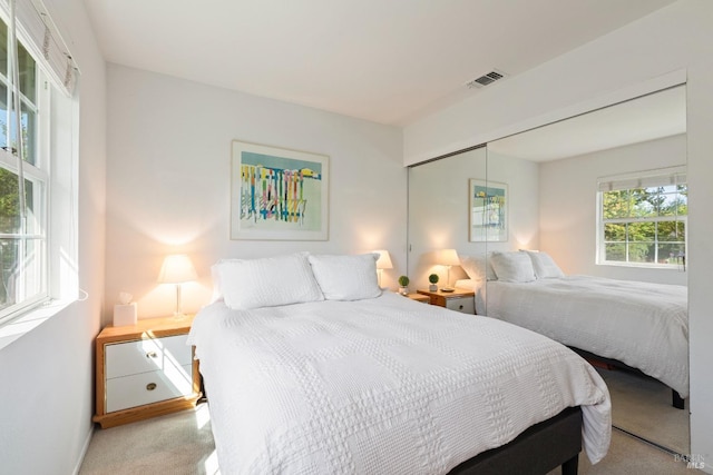 bedroom with baseboards, light colored carpet, visible vents, and a closet