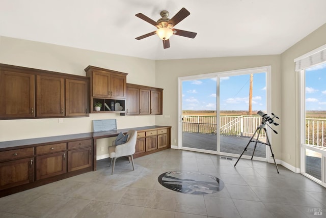 interior space featuring open shelves, lofted ceiling, built in study area, baseboards, and a ceiling fan