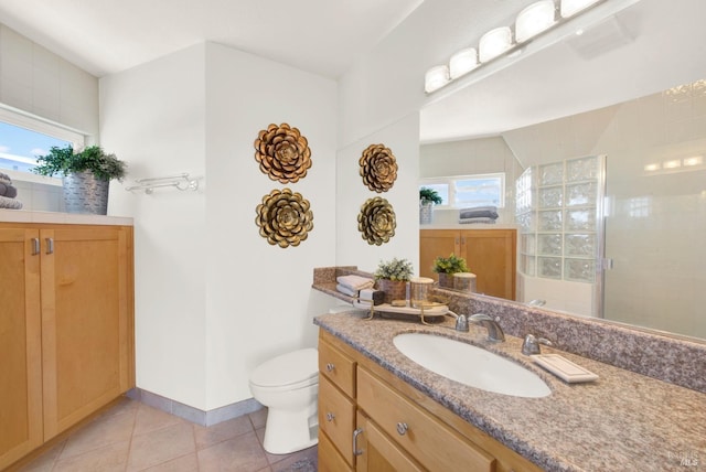 bathroom with vanity, toilet, baseboards, tile patterned floors, and a tile shower