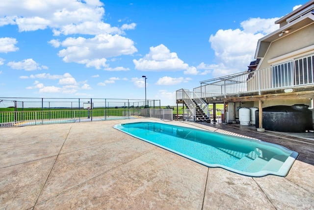 view of pool featuring fence, a wooden deck, stairway, a fenced in pool, and a patio area