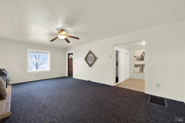 unfurnished living room featuring ceiling fan, visible vents, and carpet