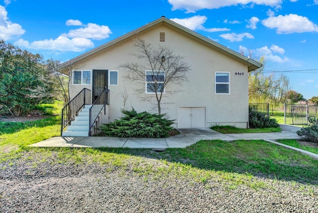 view of front of property featuring fence, a front lawn, and stucco siding