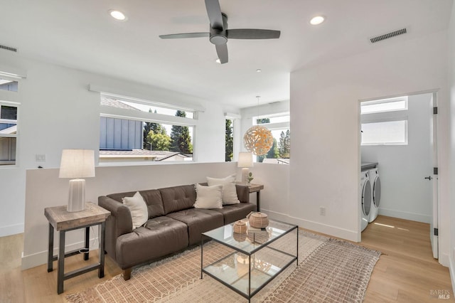 living area featuring visible vents, light wood-style flooring, baseboards, and independent washer and dryer
