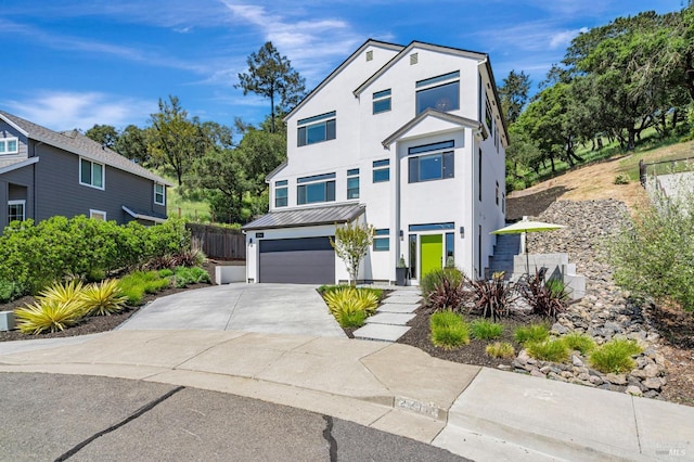 view of front facade featuring a standing seam roof, metal roof, fence, concrete driveway, and an attached garage