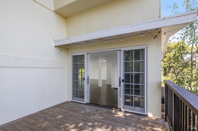 entrance to property featuring a wooden deck and stucco siding