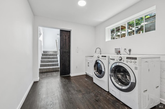 washroom with washing machine and clothes dryer, cabinet space, a sink, baseboards, and dark wood-type flooring
