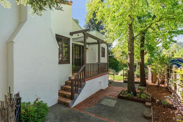 view of exterior entry featuring fence and stucco siding