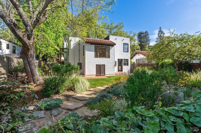 rear view of house featuring fence and stucco siding
