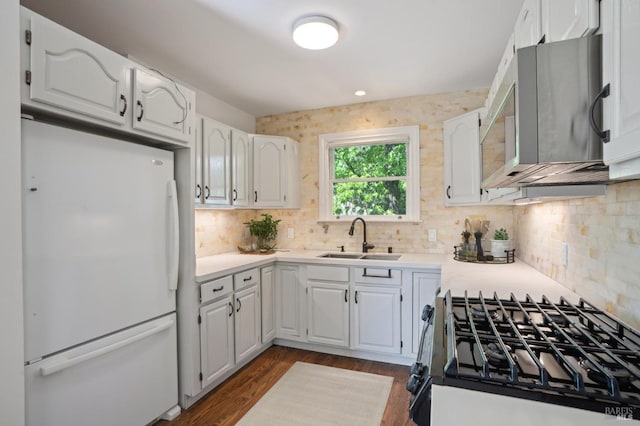 kitchen featuring freestanding refrigerator, a sink, black range with gas cooktop, and white cabinetry