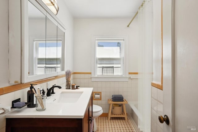 full bathroom with a healthy amount of sunlight, tile walls, vanity, and toilet