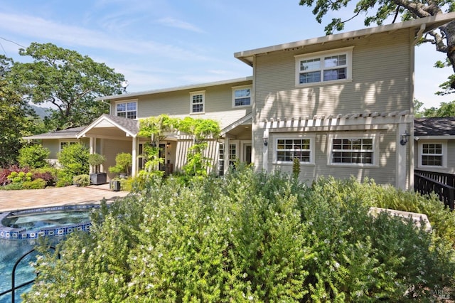 back of house featuring an in ground hot tub and a patio area