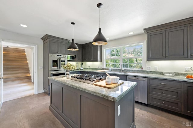 kitchen featuring a kitchen island, light stone countertops, recessed lighting, a sink, and appliances with stainless steel finishes