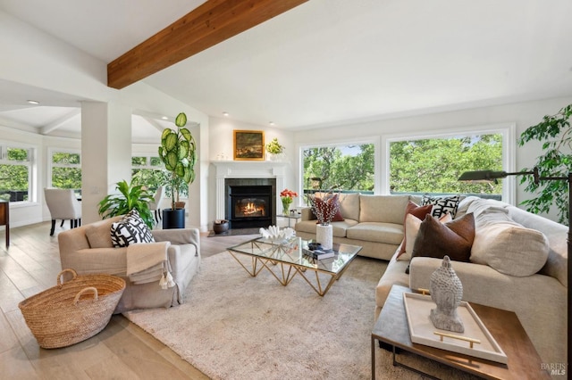 living room featuring a glass covered fireplace, wood finished floors, and beamed ceiling