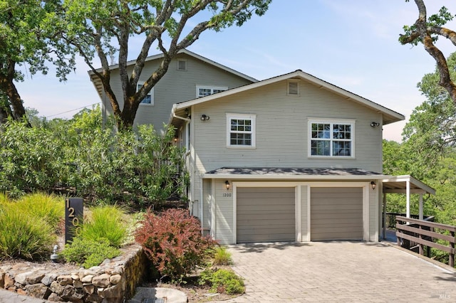 view of front of house featuring fence, an attached garage, and decorative driveway
