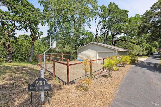 view of home's exterior with a detached garage, fence, and an outdoor structure