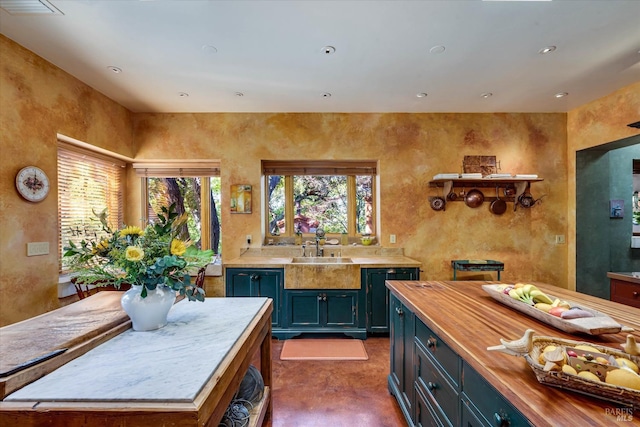 kitchen with butcher block countertops, a sink, blue cabinets, and recessed lighting