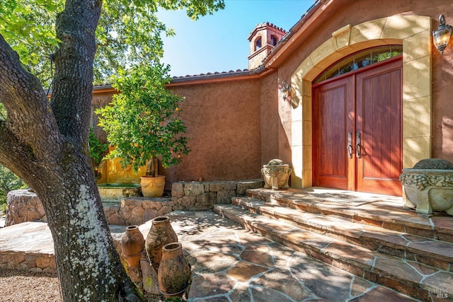 entrance to property with a tiled roof and stucco siding