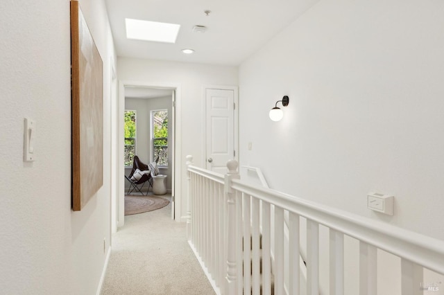 hallway with a skylight and light colored carpet
