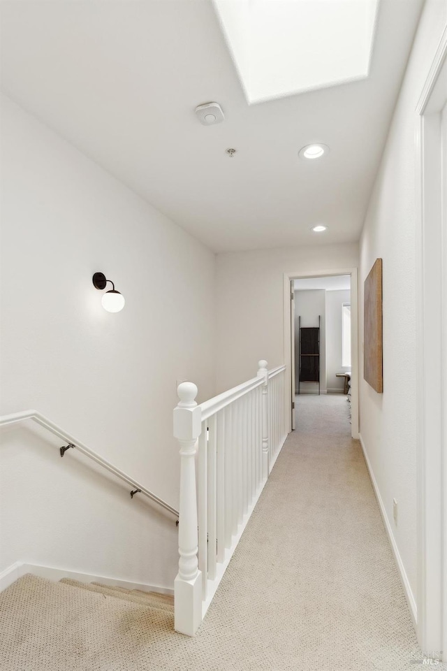 hallway featuring light colored carpet, recessed lighting, baseboards, and an upstairs landing