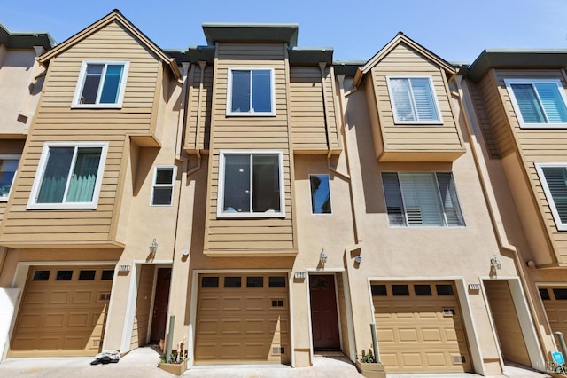 townhome / multi-family property featuring an attached garage, driveway, and stucco siding