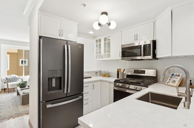 kitchen featuring light countertops, stainless steel appliances, white cabinetry, and glass insert cabinets