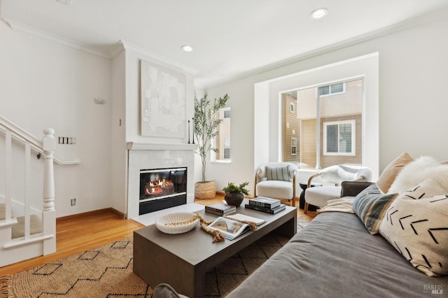 living area featuring crown molding, a premium fireplace, recessed lighting, light wood-type flooring, and stairway