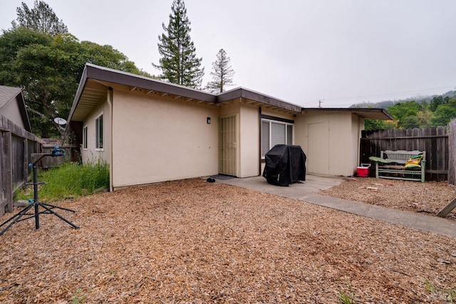 back of house with stucco siding and fence