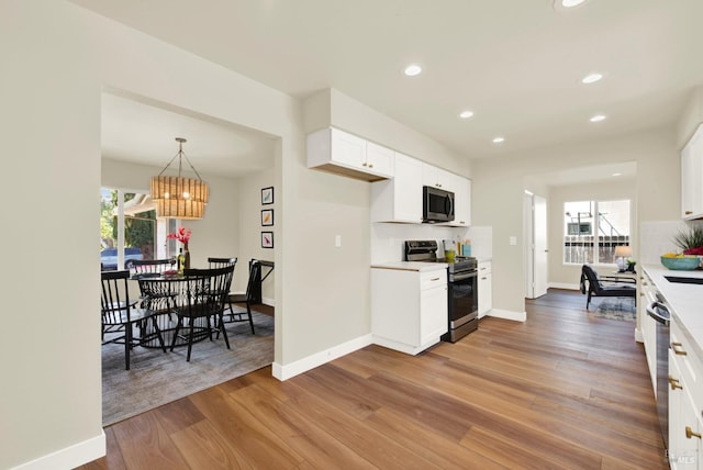 kitchen featuring wood finished floors, stainless steel appliances, white cabinetry, light countertops, and recessed lighting