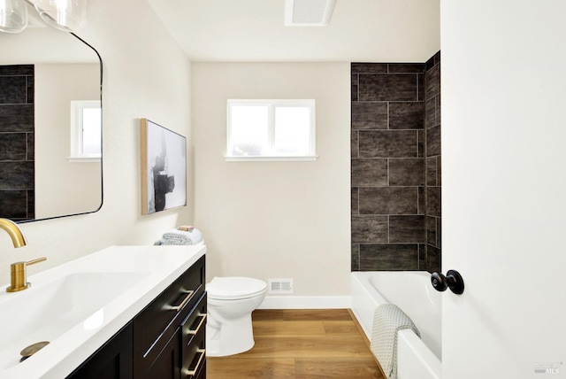 bathroom with toilet, baseboards, visible vents, vanity, and wood finished floors