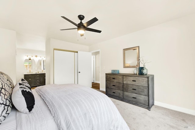 carpeted bedroom with ceiling fan, ensuite bathroom, baseboards, and a closet