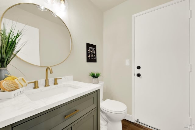 half bath with vanity, toilet, and wood finished floors