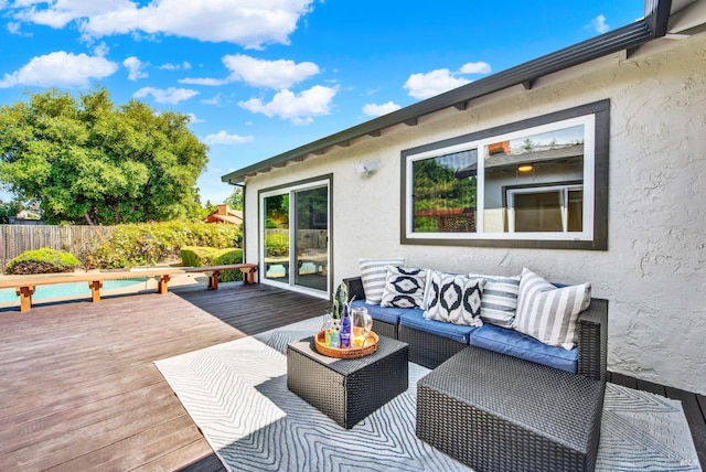 wooden deck with an outdoor hangout area, fence, and a fenced in pool