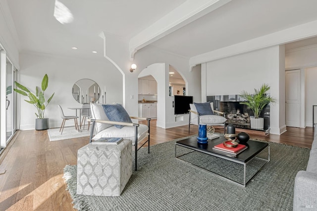 living room featuring wood finished floors, beamed ceiling, baseboards, recessed lighting, and arched walkways