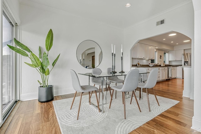 dining space featuring visible vents, arched walkways, plenty of natural light, and crown molding