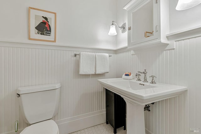 half bathroom with wainscoting and toilet