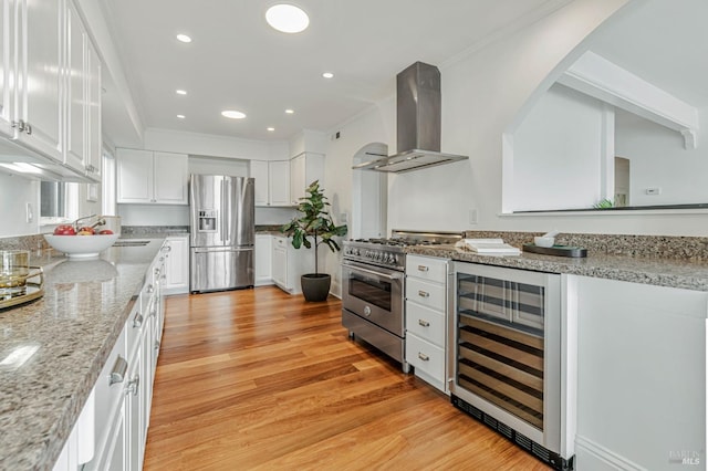 kitchen with range hood, light wood-type flooring, white cabinets, beverage cooler, and stainless steel appliances