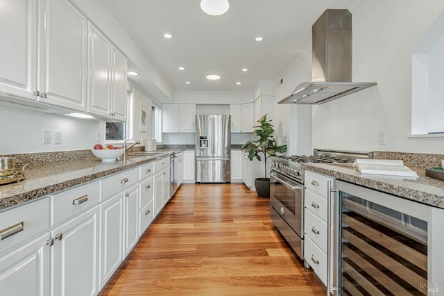 kitchen featuring stainless steel appliances, white cabinetry, beverage cooler, and range hood