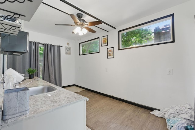 kitchen featuring a sink, baseboards, a ceiling fan, and wood finished floors