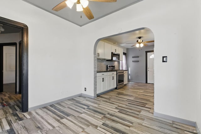 kitchen with light wood-style floors, a ceiling fan, arched walkways, and stainless steel appliances
