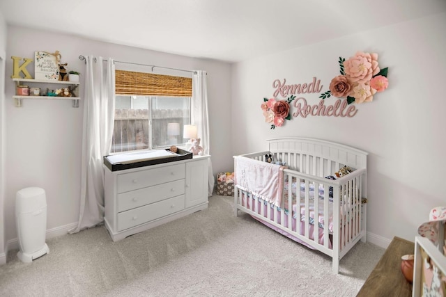 bedroom with a nursery area, baseboards, and light carpet