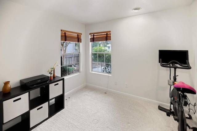 workout area with baseboards and light carpet