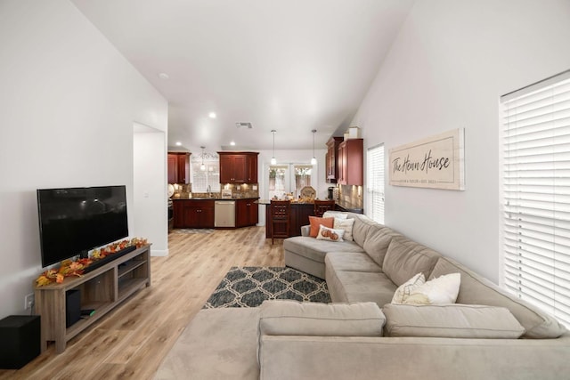 living room with visible vents, light wood-type flooring, and lofted ceiling