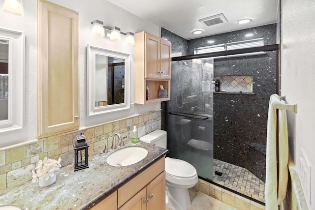 full bath with vanity, toilet, decorative backsplash, a shower stall, and visible vents