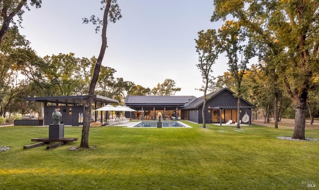 back of house featuring a yard and an outdoor pool