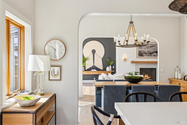 dining area featuring a chandelier, a tile fireplace, and wood finished floors