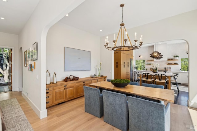 kitchen with arched walkways, plenty of natural light, light wood-type flooring, and a notable chandelier